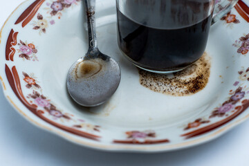 A glass of coffee and a spoon on a plate
