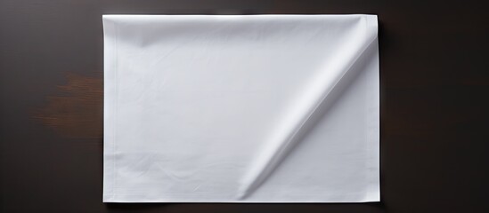 A minimalistic top down perspective of a white kitchen napkin placed on a table with no objects nearby The napkin is neatly folded creating ample blank space for customization