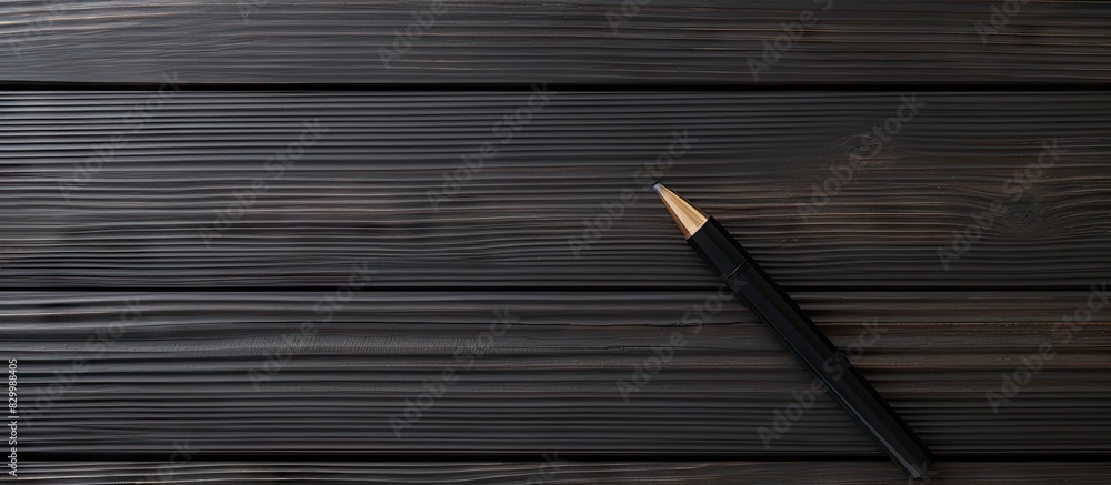 Aufkleber black wooden background with a pen in an isolated position leaving a copy space image