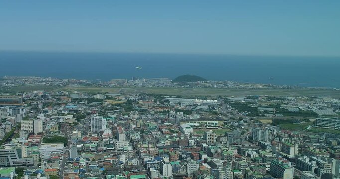 Jeju city skyline and sea with flying plane from Jeju International Airport.  In South Korea. High angle view