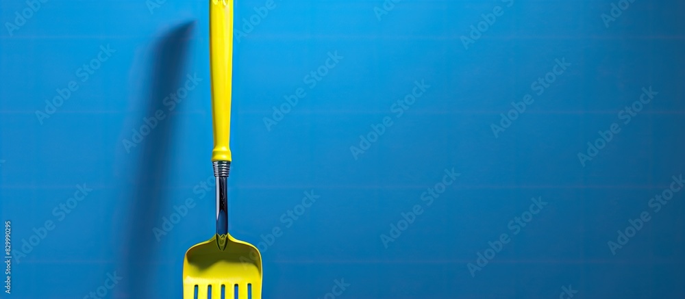 Poster A minimal concept is conveyed by a copy space image featuring a garden tool with a blue blade and a yellow fork against a green background