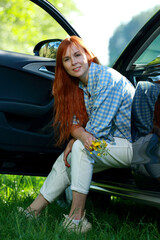 A girl poses for the camera with her car in nature. Joy, happiness, serenity. A girl with a car in nature.