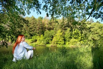 Vacation by the river. A girl strolling along the river on a beautiful summer day. Joy, happiness,The girl sees the river. serenity.