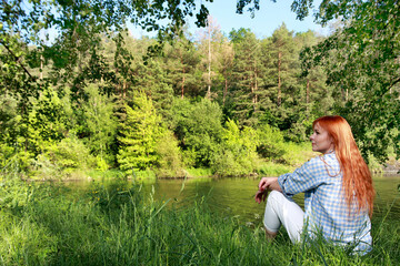 Vacation by the river. A girl strolling along the river on a beautiful summer day. Joy, happiness,The girl sees the river. serenity.