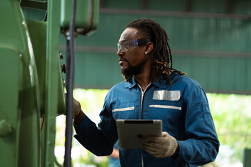 A man in a blue jumpsuit is working on a machine. He is wearing gloves and he is focused on his task