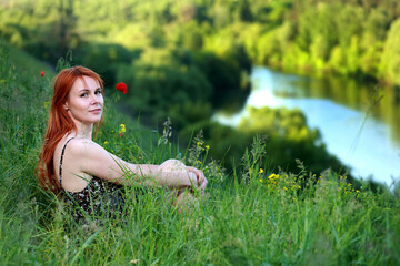 Vacation by the river. A girl strolling along the river on a beautiful summer day. Joy, happiness,The girl sees the river. serenity.