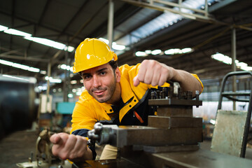 A man in a yellow and blue uniform is working on a machine. He is wearing a yellow helmet and a...