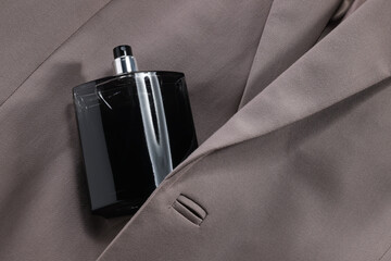 Luxury men's perfume in bottle on beige jacket, above view. Space for text