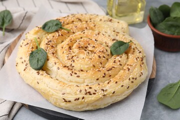 Delicious puff pastry with spinach on grey table, closeup
