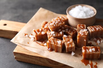 Tasty candies, caramel sauce and salt on grey table, closeup