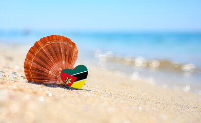 Sandy beach in Mozambique. Flag of Mozambique in the shape of a heart and a large shell. A...