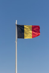 German flag attached to pole waving in the wind cloudless blue sky background