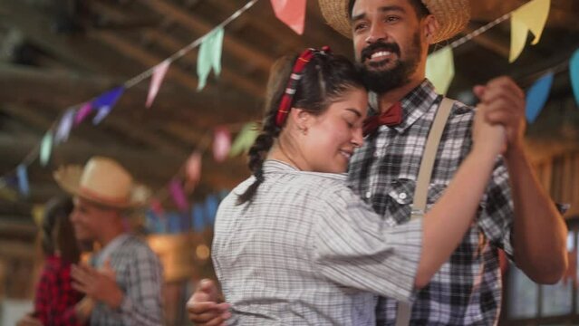 Embraced Couple dancing at Festa Junina, Love in the Air. Gentleman in a Straw Hat and Lady in Plaid, Swaying to the Melody of Brazilian Beats