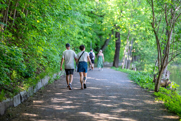 Unrecognizable people walk along river Motala Stream in waterfront park Åbackarna during spring in Norrköping, Sweden