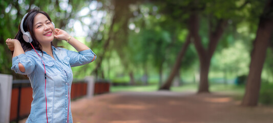 Young carefree attractive Asian woman enjoy to listening music in garden