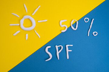 Sunscreen in the shape of a sun on a yellow background, white strokes of moisturizer. Skin health concept