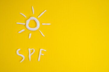 Sunscreen in the shape of a sun on a yellow background, white strokes of moisturizer. Skin health concept