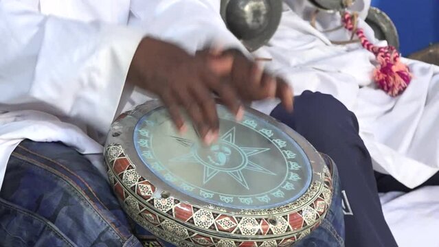 Close-up of Moroccan musicians performing traditional Gnawa music by North African goblet drum and krakeb musical instrument