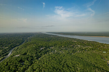 Looking Towards a City in the Distance Over a Green Forest Between a Highway and River