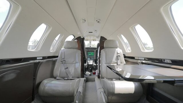 Cabin of elegant jet exuding opulence with large windows. Seating arrangement consisting of plush leather chairs facing each other over small table