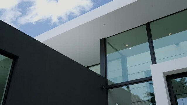 Modern commercial building under clear sky. Architecture including large glass windows and flat geometric rooflines. Dark facade creating minimalist atmosphere