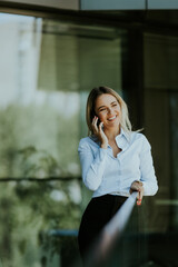 Fototapeta premium Young professional woman talking on a phone call outdoors on a sunny day
