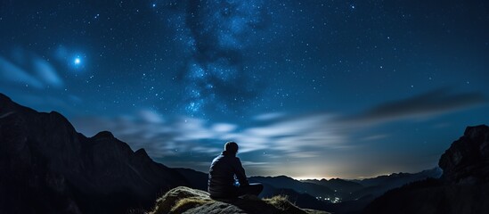 person sitting on a pile of rocks with the Milky Way night sky
