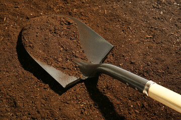 Metal shovel on fertile soil. Gardening tool