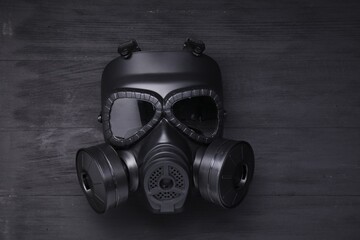 One gas mask on black wooden background, top view