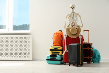 Waiting concept. Human skeleton with hat and suitcases indoors