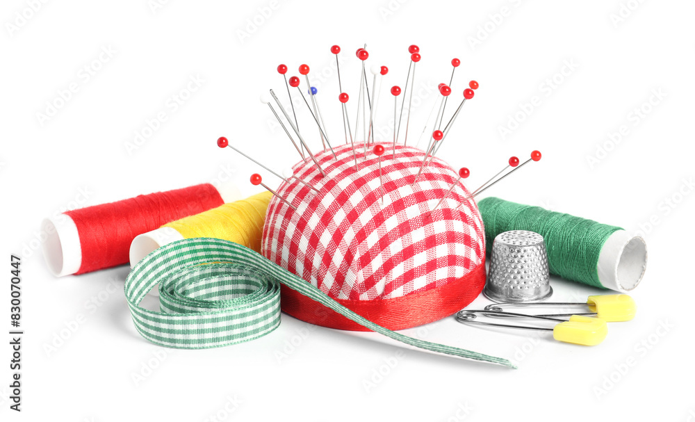 Wall mural Checkered pincushion with sewing pins, spools of threads, ribbon and thimble isolated on white