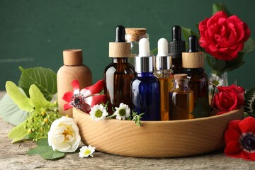 Aromatherapy. Different essential oils, flowers and green leaves on wooden table