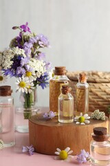 Aromatherapy. Different essential oils and flowers on pink wooden table