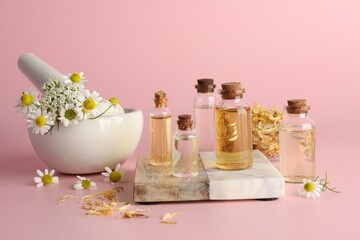 Aromatherapy. Different essential oils and flowers on pink background