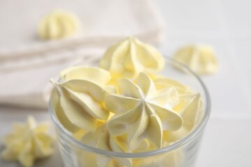 Tasty meringue cookies in glass on white table, closeup