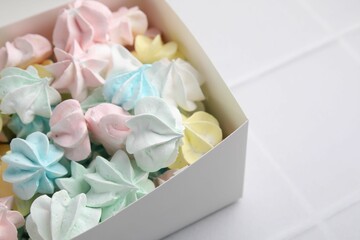 Tasty meringue cookies on white tiled table, closeup. Space for text