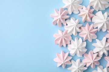 Tasty meringue cookies on light blue background, flat lay. Space for text