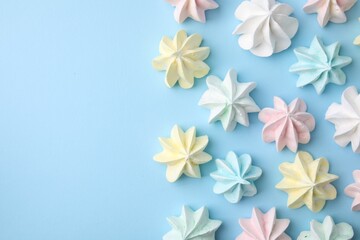 Fototapeta premium Tasty meringue cookies on light blue background, flat lay. Space for text