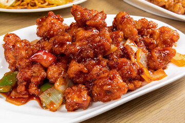 A plate of General tso chicken, a Chinese dish of breaded chicken with sweet and tangy red sauce in...