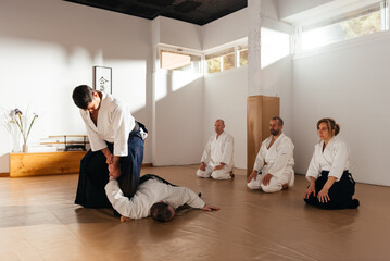 Martial Arts Sensei Demonstrates Wrist Lock Technique to Attentive Students in a Traditional Dojo Setting