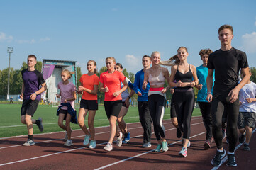 Fototapeta premium Group of young athletes training at the stadium. School gym trainings or athletics
