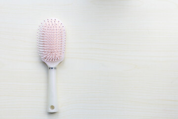 A flat lay of a hairbrush with white bristles resting on the table.