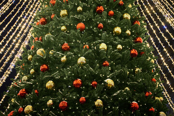 Festive New Year Christmas tree decorated red yellow Christmas balls with garlands lights, close up...