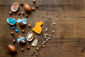 Chocolate Easter eggs in blue ribbon and bunny cookies on wooden background