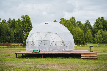 Experience a geodesic dome tent on a wooden platform in a tranquil natural setting, perfect for a serene and sustainable ecofriendly retreat amid verdant surroundings © Aleksey