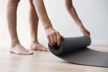 Woman rolling up exercise mat and preparing practicing yoga. Young woman is going meditating or...