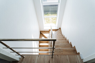 Featuring a modern wooden staircase with a stainless steel handrail and large window, this home design creates a bright, spacious interior with a contemporary minimalist aesthetic