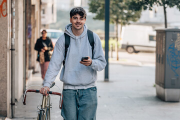 student with mobile phone on the street walking with the vintage bicycle