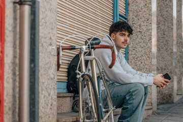 urban cyclist sitting on the street with mobile phone