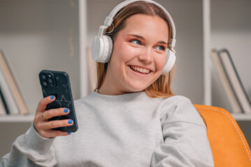 girl or young woman at home smiling with mobile phone and headphones